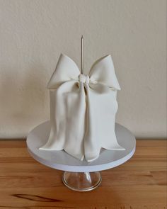 a white cake with a large bow on it's top sitting on a plate