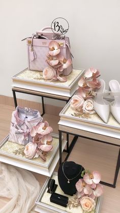 three small tables with flowers and shoes on them, one is white the other is pink