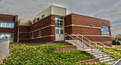 a brick building with green grass on the ground and stairs leading up to it's entrance