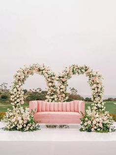 a pink couch sitting on top of a lush green field next to a flower covered bench