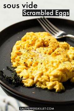 scrambled eggs on a black plate with a fork and knife next to it text reads, sous vide scrambled eggs