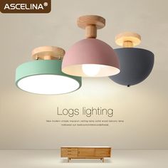 three different colored lights hanging from the ceiling above a wooden bench with a white background