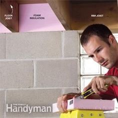 a man in a red shirt is using a yellow and pink box to measure the wall