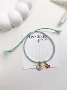 🐚 Sandy toes and sea shell dreams! This beautiful summer bracelet features 18K gold plated charms in a handmade adjustable glitter cotton rope cord. 😎 ITEM DETAILS  🌴 18K Gold plated charms 🌴 Cotton cord rope 🌴 Nylon cord All of our bracelets are handmade with high quality materials. The listing is for one bracelet, images showing more than one are an example of how they would look stacked with other bracelets. If you have any questions, please feel free to message me. CARE TIPS 🤍 Keep your jewelry dry and away from perfumes or any harsh chemicals 🤍 Store your jewelry separately, and avoid wearing it if you are going to work out. Thank you so much for visiting my shop! 🤍 Have fun creating your favorite combinations and enjoy your new jewelry!  Follow me on instagram: @tropicalpink_ Gold Shell-shaped Bracelet For Vacation, Adjustable Beaded Bracelets With Charms For Beach, Gold Shell Bracelet For Vacation, Adjustable Gold Beaded Bracelets For Beach Season, Adjustable Charms Bracelets For Beach, Adjustable Charm Bracelets For Beach, Ocean-inspired Gold Bracelets For Beach Season, Gold Resizable Beaded Bracelets For Vacation, Handmade Gold Braided Bracelet For Vacation