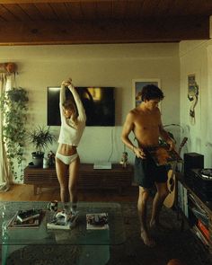 two people standing in a living room playing guitars