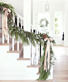 the stairs are decorated with greenery and pine cones for garlands on each handrail