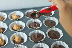 someone is decorating chocolates in their cupcake tins with a red spatula