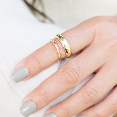 a woman's hand with two gold rings on her left and one silver ring on her right