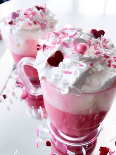 two cups filled with whipped cream and sprinkles on top of a table