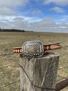 a brown belt sitting on top of a wooden post in front of a grass field