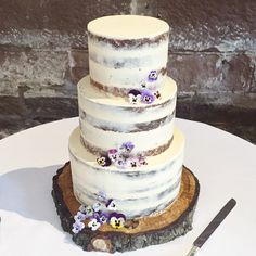 a three tiered cake sitting on top of a wooden slice