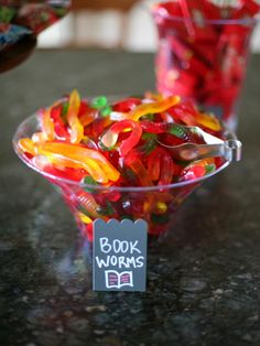 a glass bowl filled with gummy bears sitting on top of a counter next to a sign that says book worms