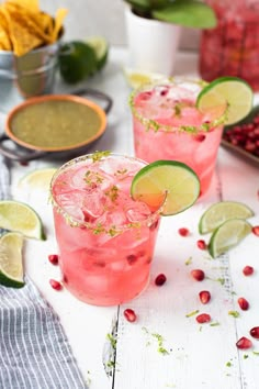 two glasses filled with pink lemonade, lime and pomegranate garnish