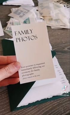 a person holding up a family photos card on top of a table with papers all over it