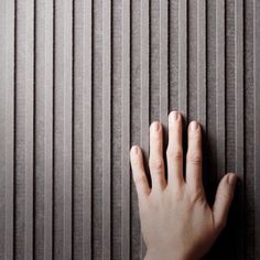 a person's hand on the wall with vertical blinds