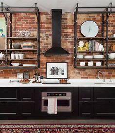 a kitchen with brick walls and open shelving on the wall, along with an area rug