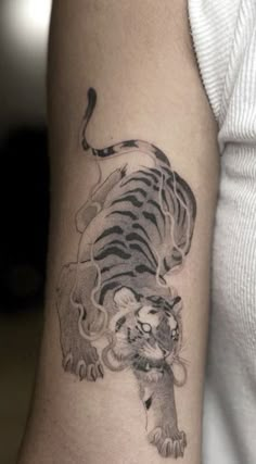 a black and white tiger tattoo on the right arm, with an animal in it's claws