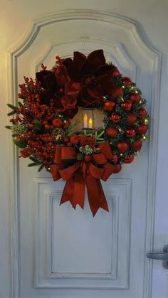 a wreath on the front door decorated with poinsettis and christmas decorations is lit by a candle