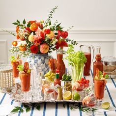 an assortment of fruits and vegetables on a table with drinks in vases next to each other