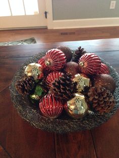 a bowl filled with christmas ornaments on top of a wooden table