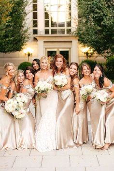 a group of women standing next to each other in front of a building with bouquets