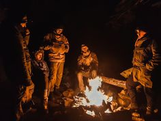 group of people standing around a campfire at night