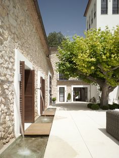 a woman walking her dog down the street in front of a house with stone walls