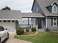 a car is parked in front of a house with two garages and a porch