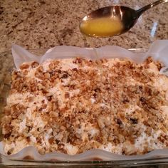 a glass dish filled with food on top of a counter next to a metal spoon