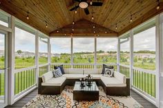 a screened porch with couches, tables and ceiling fans on the outside side of it