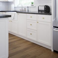 a kitchen with white cabinets and black counter tops