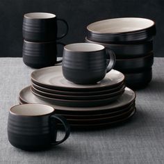 a stack of black and white dishes with brown rims