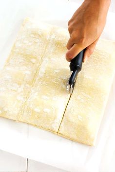 a person is cutting up some food on a piece of parchment paper with a knife