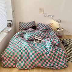 a bed covered in pink and green checkered comforter next to a black and white floor