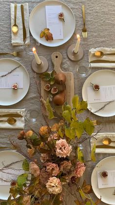 the table is set with white plates, silverware and pink flowers in vases