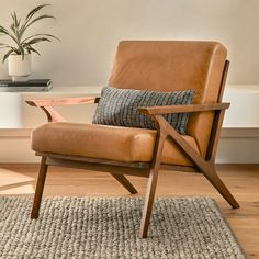 a brown leather chair sitting on top of a rug next to a potted plant