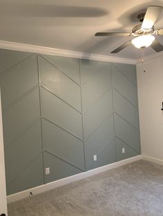 an empty room with a ceiling fan and wallpaper on the walls in front of it