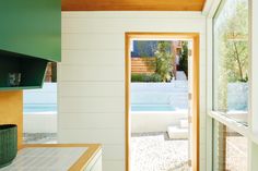 an open door leading to a pool in a house with white walls and wood floors