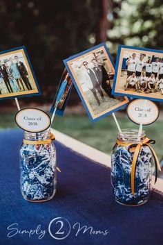 two mason jars with pictures in them are sitting on a blue cloth covered tablecloth