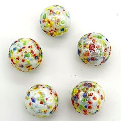 four white and multicolored glass bead balls with sprinkles on them