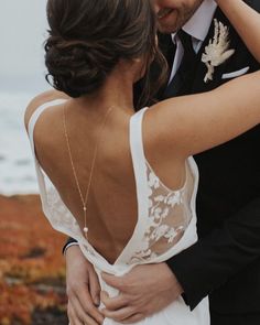 a bride and groom embracing each other in front of the ocean