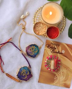 a card, necklaces and candle on a white sheet next to some other items