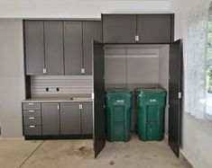 an empty garage with two trash cans in the middle and one green bin on the other side