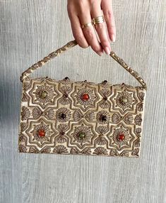 This stunning vintage gemstone purse is handcrafted in India in the 1940's. This purse is a rare piece of art. It is made of velvet covered in gold metallic embroidered, and colored glass gemstone on both sides. The interior is silk and has a snap clasp close. The purse is labelled handmade in India.  * 1940s  * Metallic embroidered * Cabochon gemstones  * Beige velvet covered in gold * Handcrafted in India  * Measurements  8 inches by 5 inches * Natural signs of wear are normal for vintage pieces. Each piece in our shop has stood the test of time.  All sales are final - refunds are not accepted. * PRE-LOVED: Buying this item reduces the environmental impact of using new resources. Thank you for making a better choice for the planet. Indian Purse, Vintage Indian, Clutch Purse, Clutch Handbag, New Bag, Evening Bags, Colored Glass, Needle Felting, Purses And Handbags