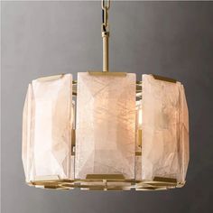 a chandelier hanging from the ceiling with three shades of white and gold on it