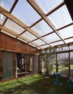 the inside of a house with lots of windows and grass on the ground in front of it