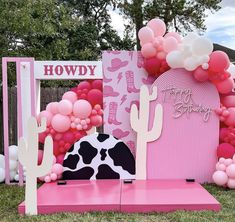 a pink and black cow themed birthday party with balloons, paper cutouts, and decorations