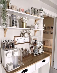 a kitchen with white cabinets and shelves filled with coffee cups, mugs and other items