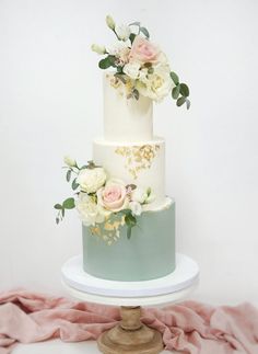 a white and blue wedding cake with flowers on top