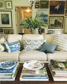 a living room filled with furniture and lots of pillows on top of each other in front of pictures